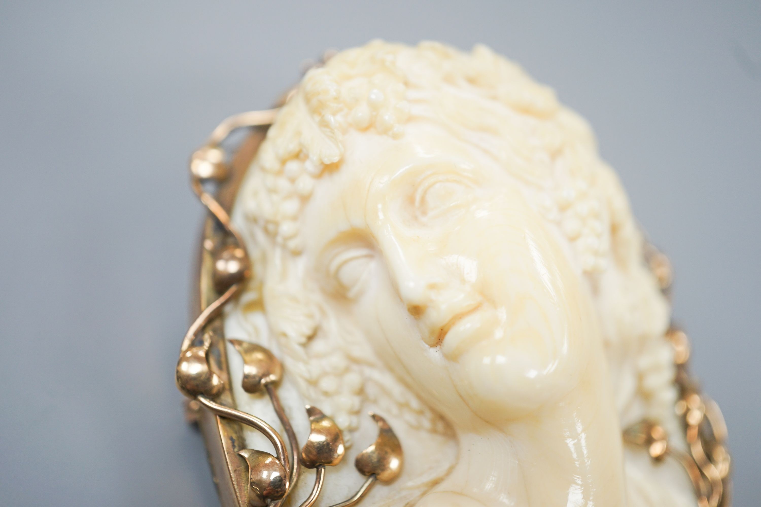 An early 20th century yellow metal mounted oval ivory cameo pendant brooch, carved with the bust of a lady, 68mm, gross weight 70 grams.